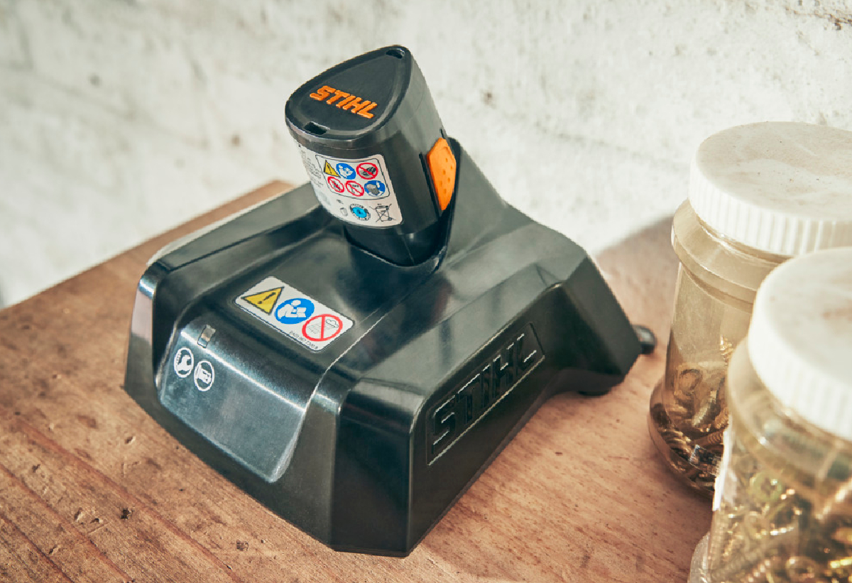 Απεικονίζεται ο φορτιστής πάνω σε πάγκο να φορτίζει μια μπαταρία.